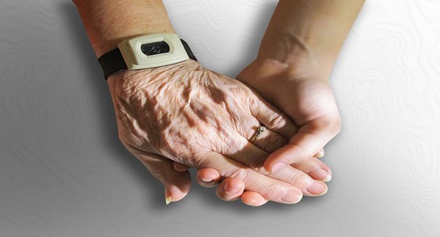 Image of a person holding an Alzheimer’s patient’s hand.