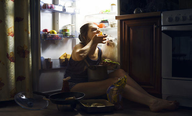 emotional eater girl sitting in front of fridge and eating