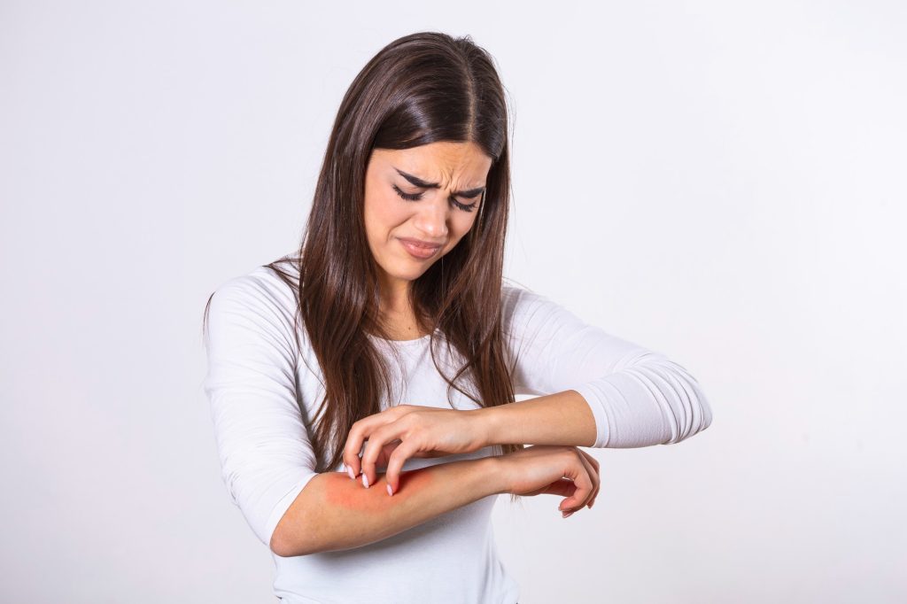 young-woman-scratching-her-arm-due-itching-gray-background