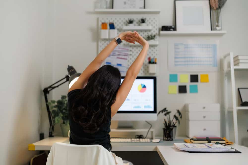 Businesswoman,Stretching,Arms,At,Desk,After,Working,On,Computer,,Taking
