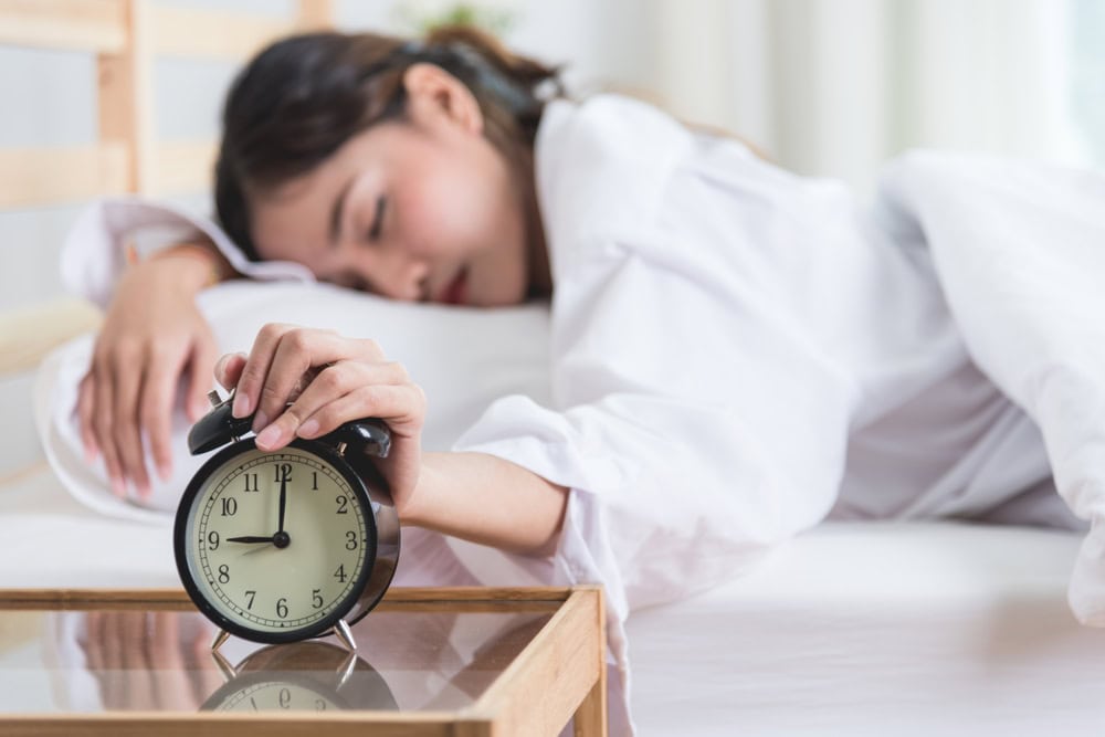Asian,Young,Woman,Lazy,Sleepy,On,Bed,With,Ringing,Alarm