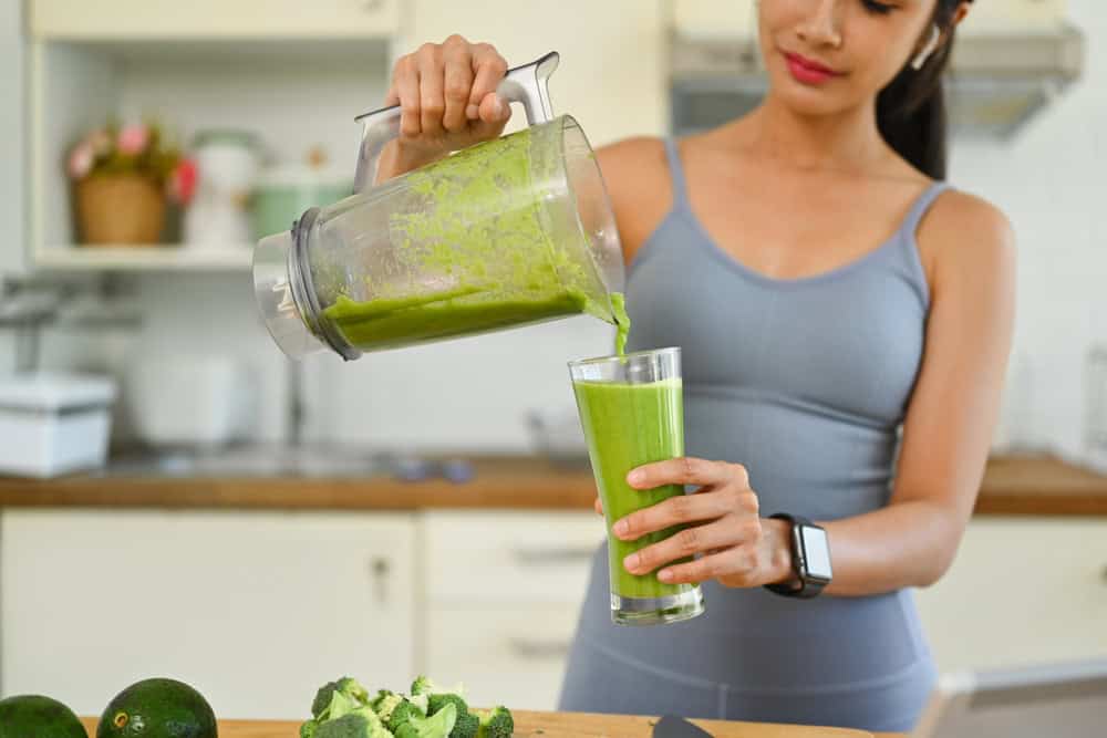Young,Sporty,Woman,Pouring,Green,Detox,Smoothie,Into,Glass.,Dieting