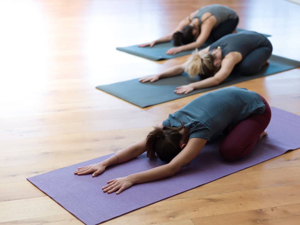 Women,Practicing,Yoga,Together,And,Performing,The,Child's,Pose,On