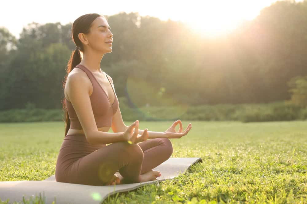 Beautiful,Young,Woman,Practicing,Padmasana,On,Yoga,Mat,Outdoors,,Space